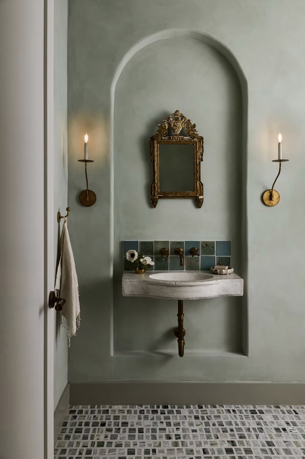 Powder bath with plaster arched niche, antique gilt mirror, candle sconces and floating stone sink