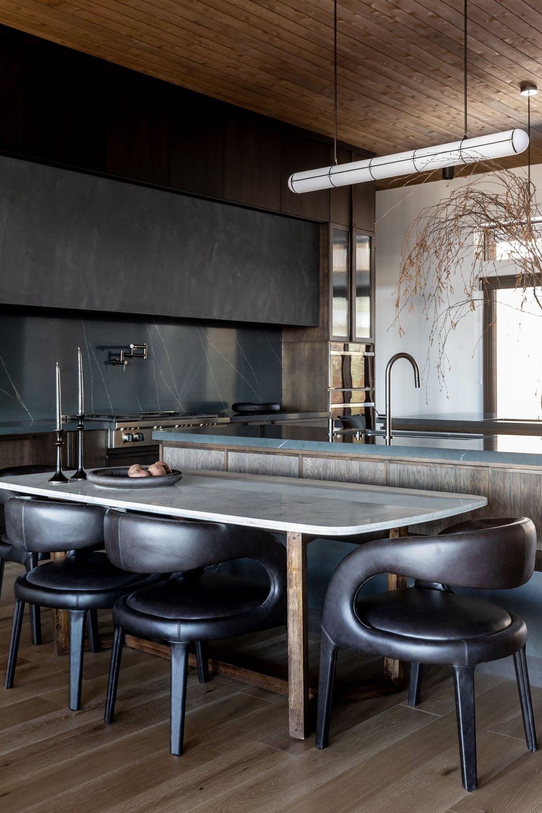 Marble-topped kitchen table with sculptural leather chairs beside the island
