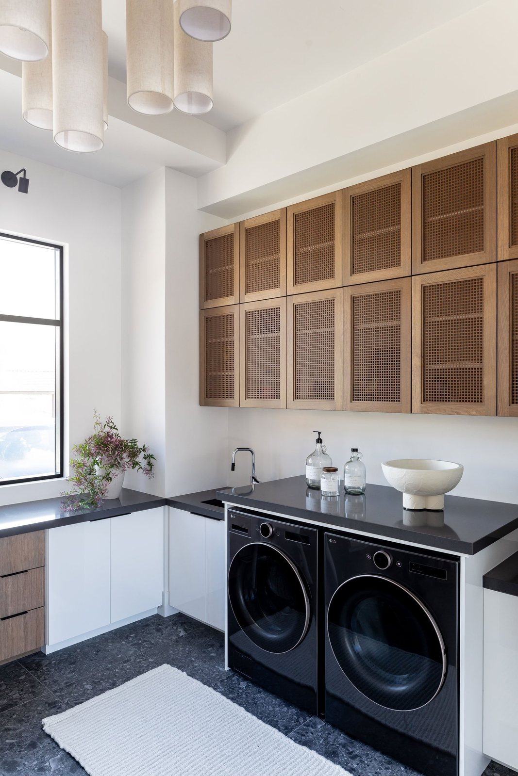 Laundry room with oak grid-front cabinets, charcoal counters and terrazzo floor