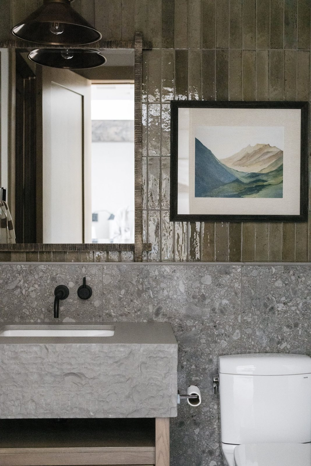 Bath with glossy green vertical tile, terrazzo wainscot and chiseled stone sink
