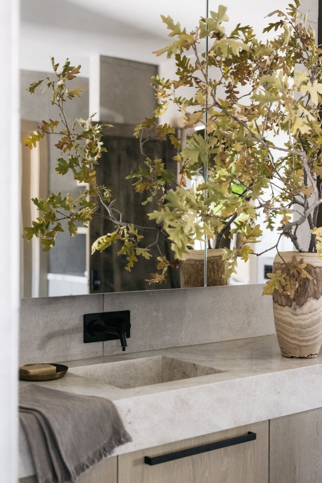 Vanity with integrated limestone sink and matte black wall faucet