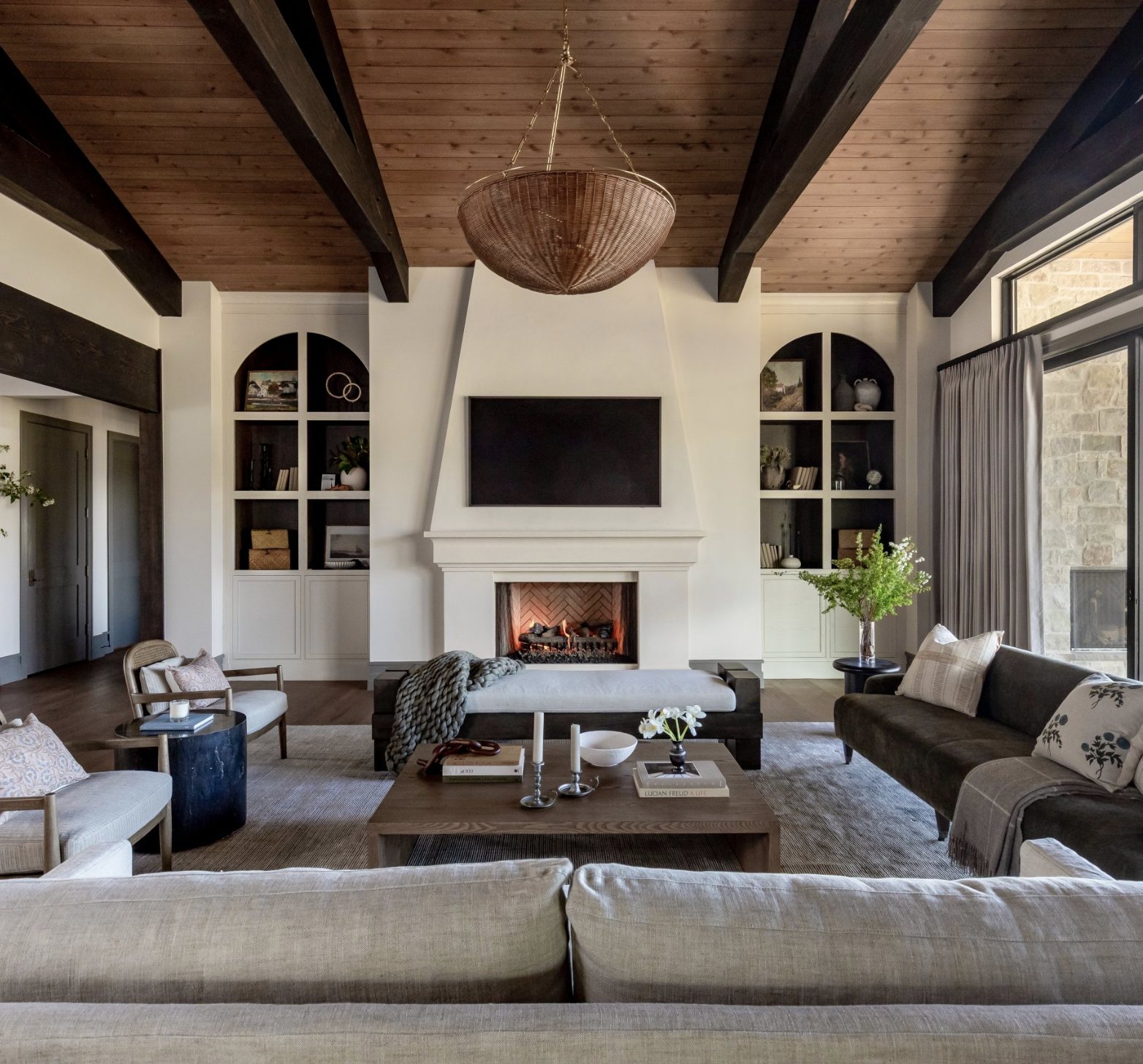 Mountainside great room with plaster fireplace, arched built-ins and dark timber beams