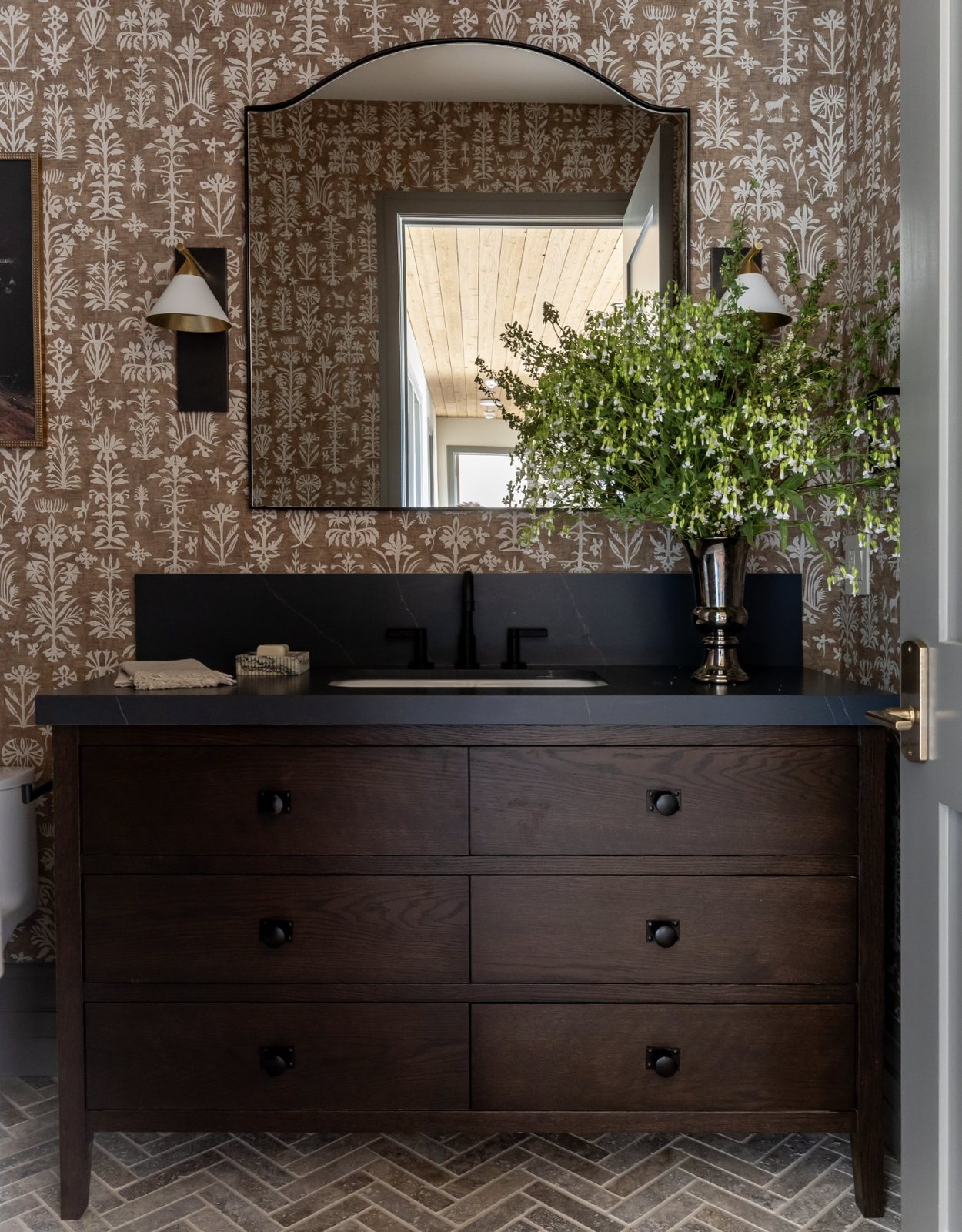 Powder bath with folk-pattern wallpaper, dark oak vanity and arched mirror