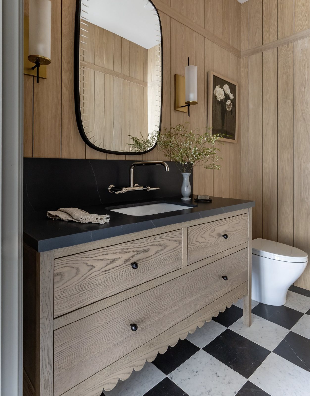 Powder bath with white oak paneling, scalloped oak vanity and checkerboard marble floor